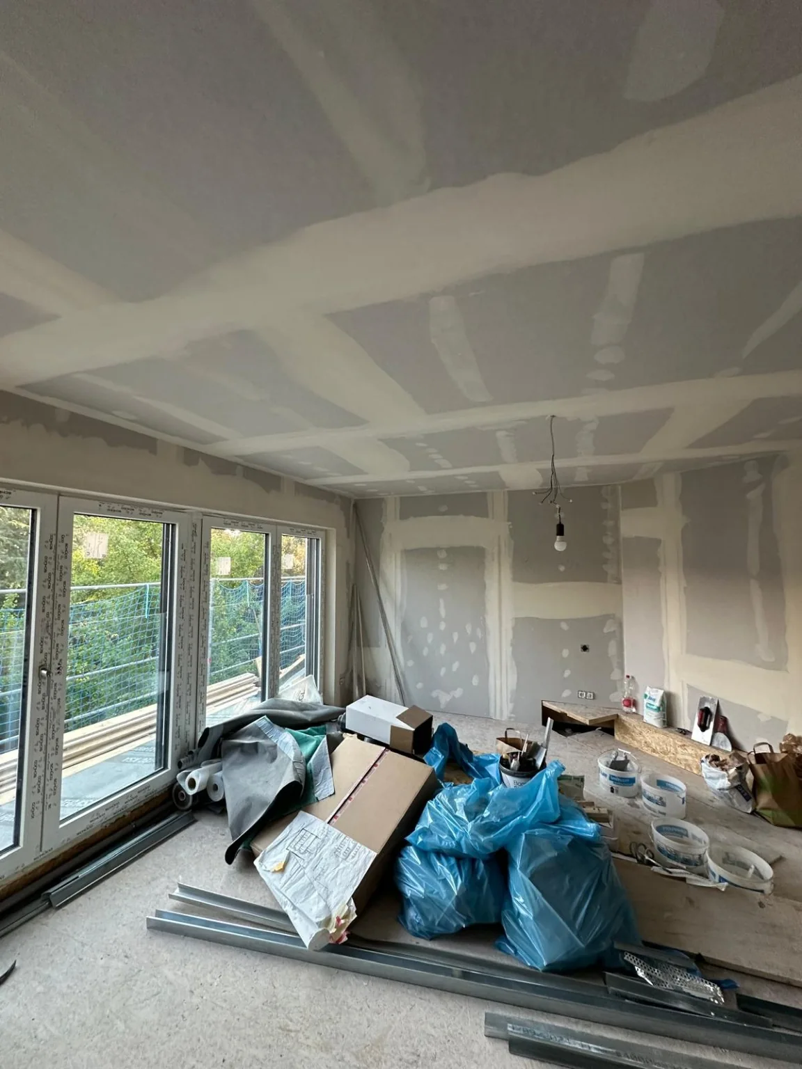 Gipskarton-Decke und Wandflächen im Dachgeschossraum mit bodentiefen Fenstern