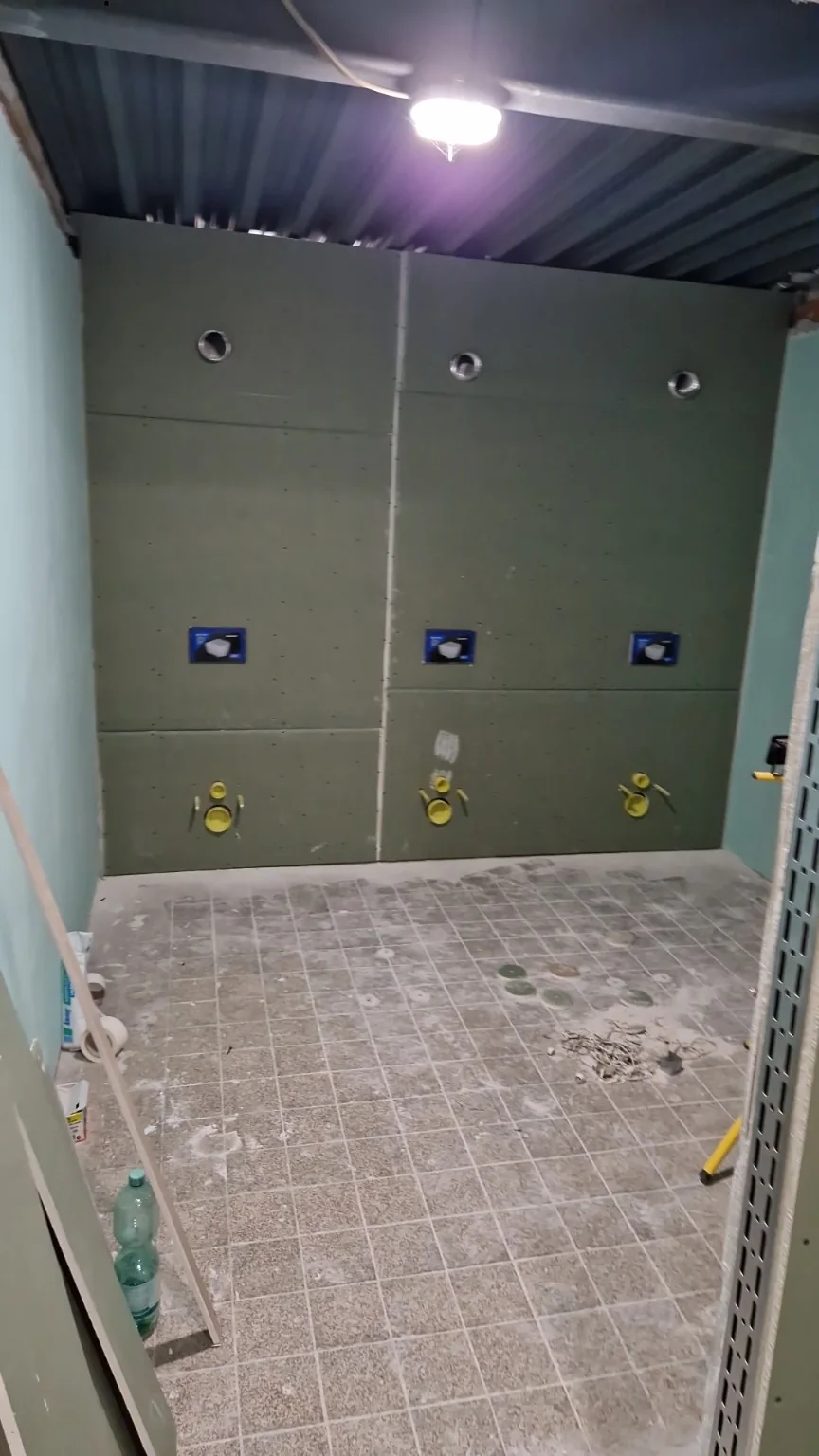 Gipskartonbeplankte Wand in einem Sanitärraum mit vorbereiteten Installationsöffnungen